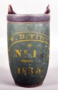 2. Though it rarely shows up in pictures because of how they are always displayed resting on flat surfaces, don’t be surprised if your fire bucket has a slightly convex, round bottom. It’s not a condition flaw, it was a practical element that made the bucket more efficient. According to the New York Fire Museum, a rounded bottom resulted in a more controlled stream of water when throwing it on a fire. photo: Conestoga Auction Company.