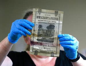 Conservator Kate Ridgeway holds a pamphlet titled “The Immigrant’s Friend,” one of the artifacts inside a copper box time capsule below the Robert E. Lee memorial.